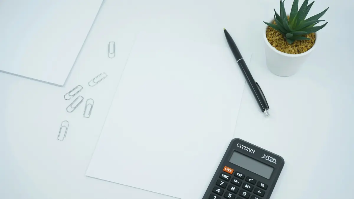 black calculator beside black pen on white printer paper
